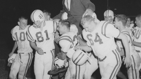 Athletes holding up Coach Tom Hamilton